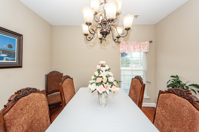 dining room with dark hardwood / wood-style flooring and an inviting chandelier