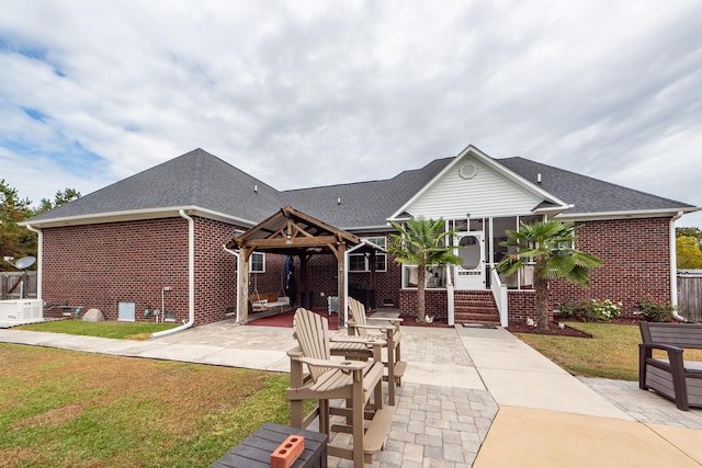 rear view of property featuring a gazebo, a patio area, a yard, and central AC unit