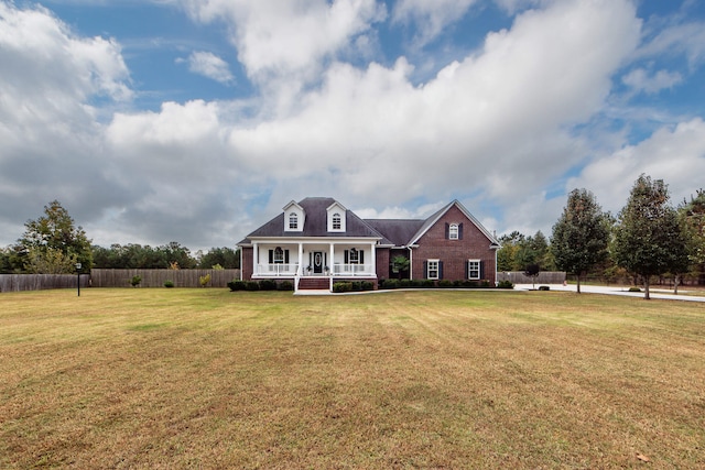 cape cod home featuring covered porch and a front lawn