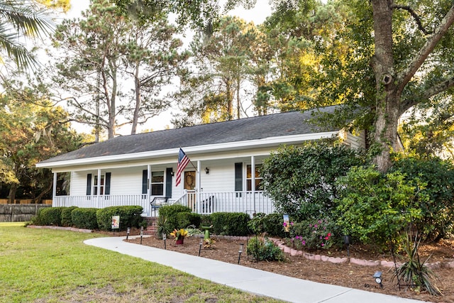 ranch-style house featuring a shingled roof, a front lawn, and covered porch