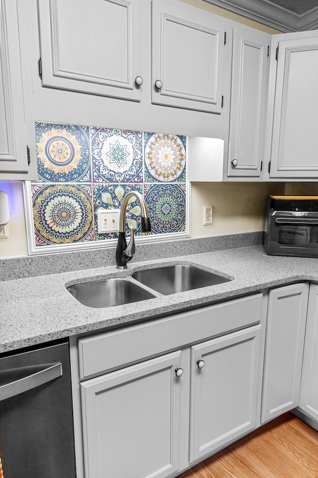 kitchen with white cabinets, a toaster, light stone counters, stainless steel dishwasher, and a sink