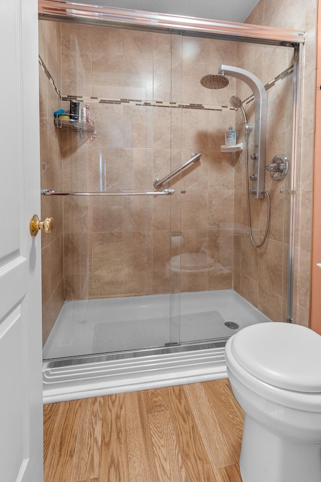 bathroom featuring a shower with door and toilet