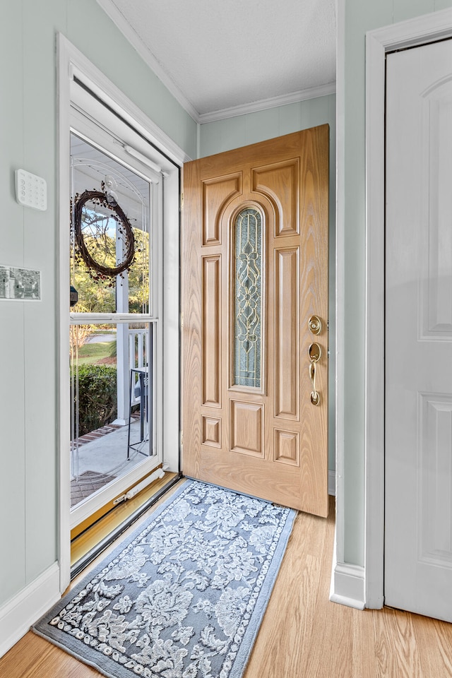 foyer entrance with crown molding, light hardwood / wood-style flooring, and a textured ceiling