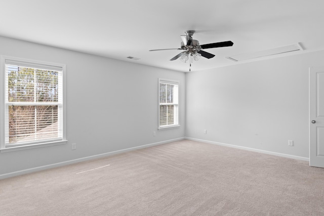 empty room with light colored carpet, a healthy amount of sunlight, visible vents, and baseboards