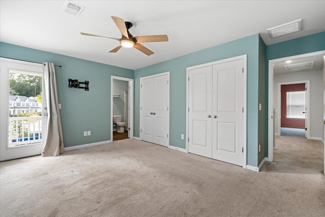 unfurnished bedroom with light carpet, two closets, ensuite bathroom, and ceiling fan