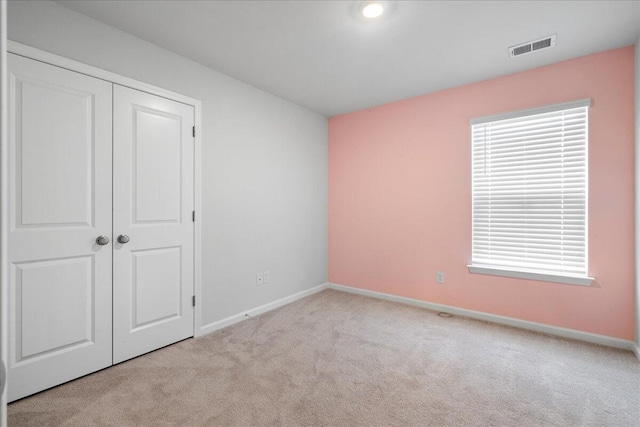 unfurnished bedroom with a closet and light colored carpet