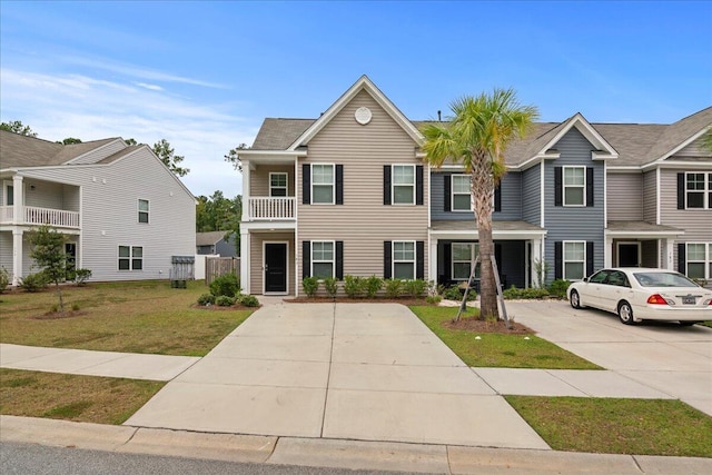 view of property featuring a balcony and a front lawn