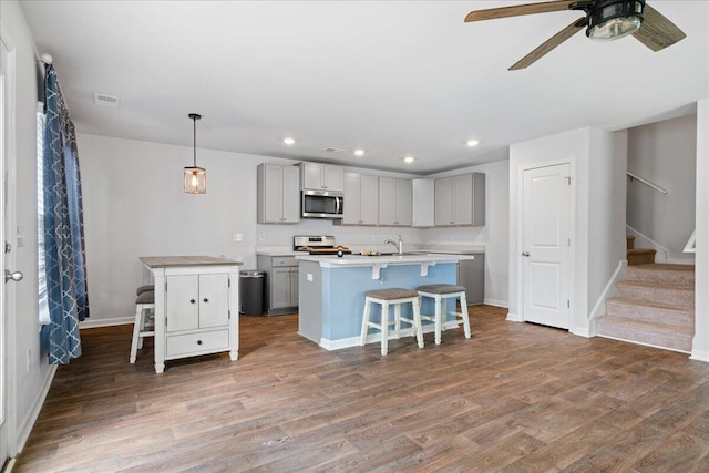 kitchen featuring hardwood / wood-style floors, pendant lighting, stove, and an island with sink