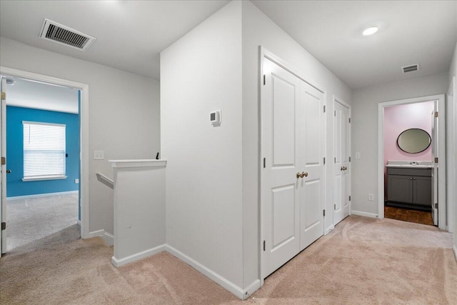 corridor with sink and light colored carpet