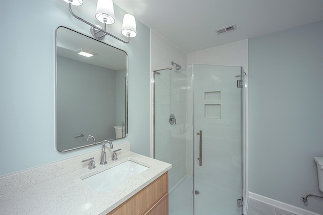 bathroom featuring vanity, toilet, and a shower with shower door