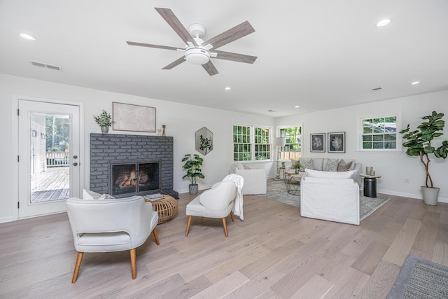 living room with a fireplace, ceiling fan, and light hardwood / wood-style flooring