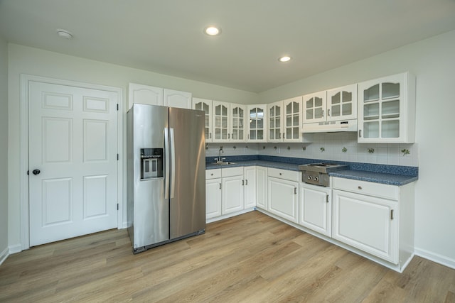 kitchen with backsplash, sink, light wood-type flooring, appliances with stainless steel finishes, and white cabinetry