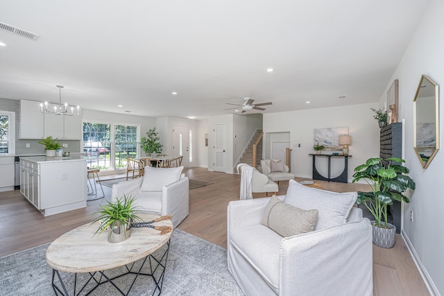 living room featuring ceiling fan with notable chandelier and light hardwood / wood-style floors