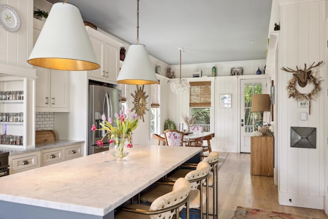 732 Gate Post Dr, Mount Pleasant, SC 29464 - kitchen with stainless steel fridge with ice dispenser, light wood finished floors, white cabinetry, a kitchen island, and a kitchen bar
