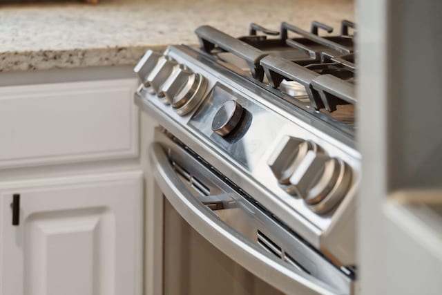 interior details featuring stainless steel range with gas cooktop and light stone countertops