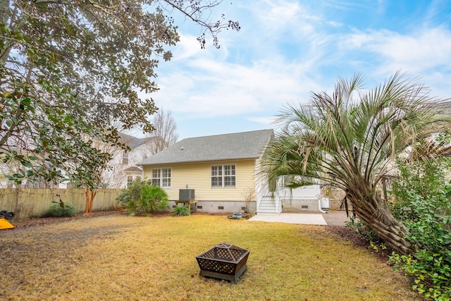 rear view of property featuring a lawn, central AC, a patio area, and an outdoor fire pit