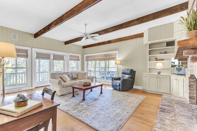 living area with visible vents, beamed ceiling, light wood-type flooring, and a ceiling fan