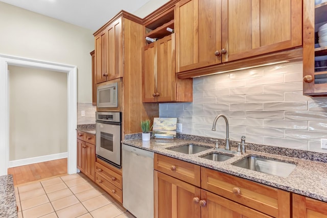 kitchen with open shelves, stainless steel appliances, backsplash, and brown cabinetry