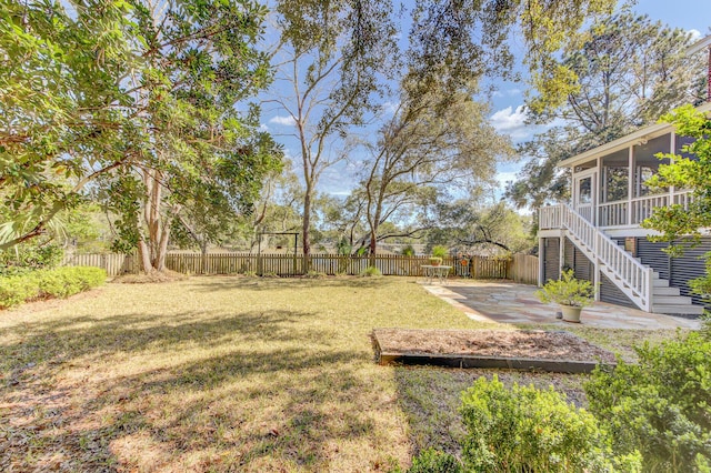 view of yard featuring a fenced backyard, stairway, a patio, and a sunroom