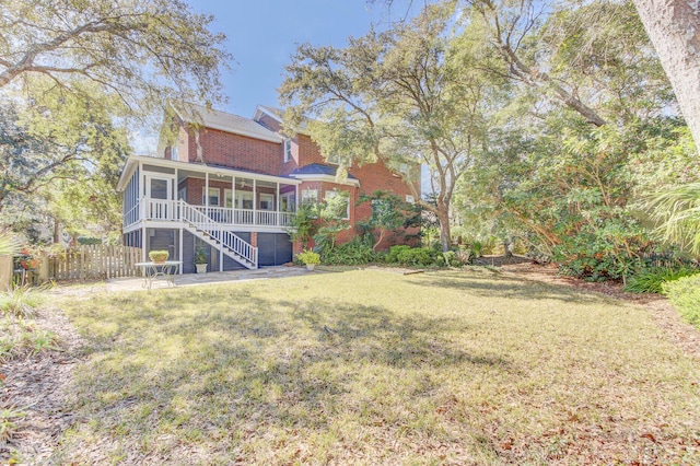 view of yard featuring fence, stairs, and a sunroom