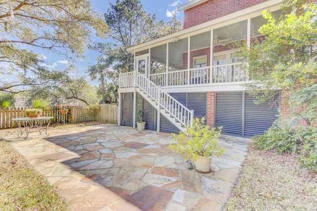 back of property featuring fence, a patio area, brick siding, and a sunroom