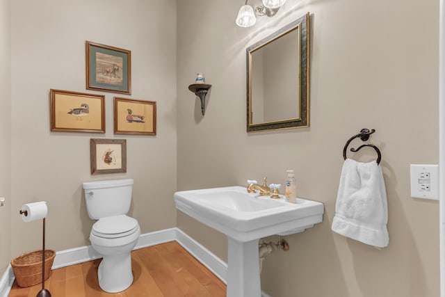 bathroom featuring toilet, wood finished floors, and baseboards