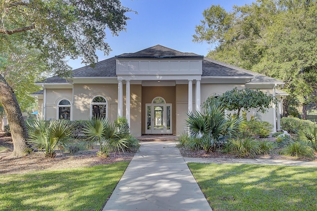 view of front of property with stucco siding, a shingled roof, and a front lawn