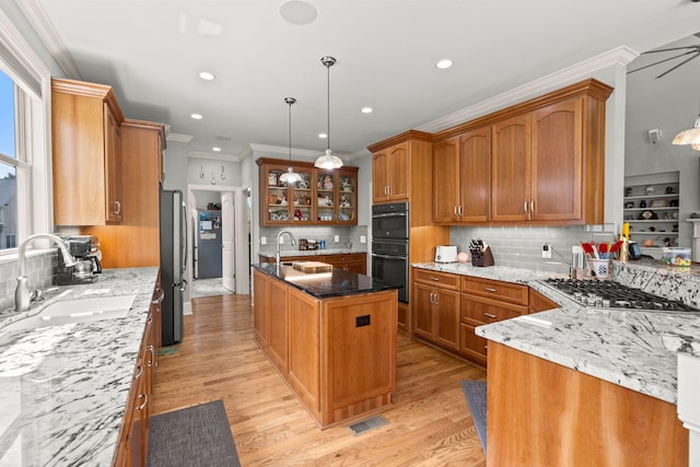 8605 Refuge Point Cir N, Charleston, SC 29420 - kitchen with a sink, appliances with stainless steel finishes, crown molding, brown cabinetry, and decorative backsplash