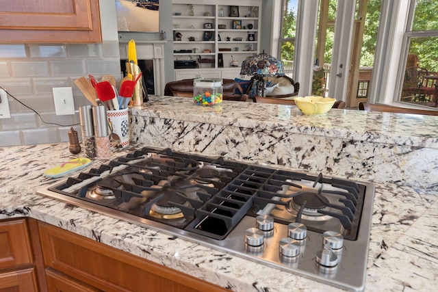 8605 Refuge Point Cir N, Charleston, SC 29420 - kitchen view of backsplash, stainless steel gas cooktop, brown cabinetry, and light stone counters