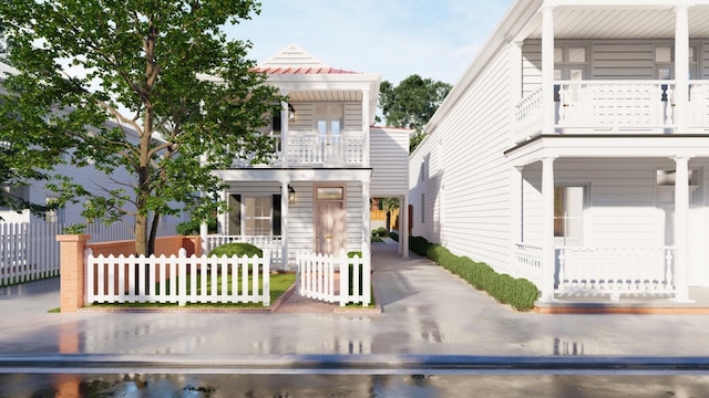 view of front of property featuring a balcony, a fenced front yard, and covered porch