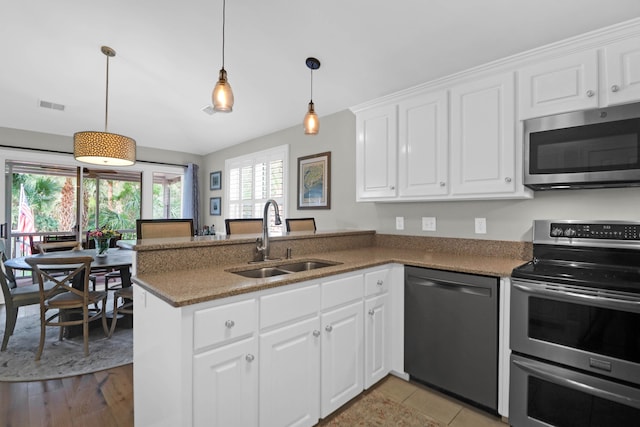 kitchen featuring white cabinets, light wood-type flooring, stainless steel appliances, sink, and kitchen peninsula