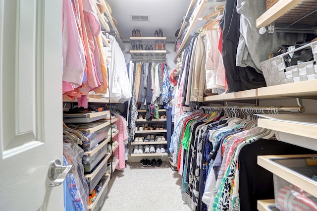 walk in closet featuring light colored carpet