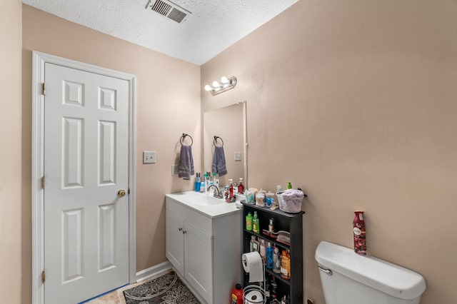 half bathroom with baseboards, visible vents, toilet, a textured ceiling, and vanity