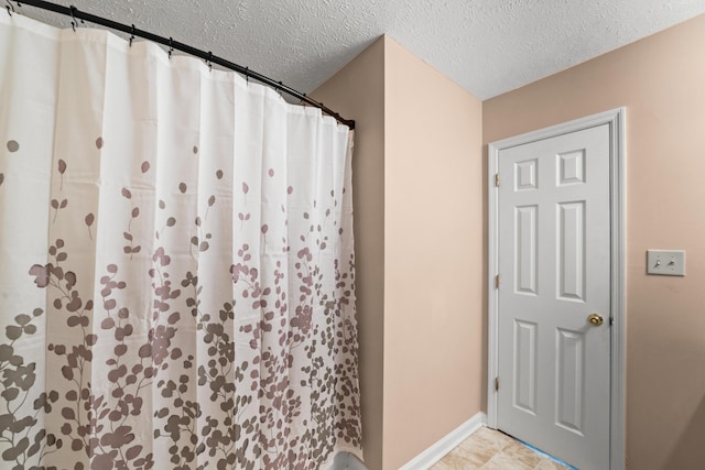 bathroom with baseboards, a textured ceiling, and a shower with shower curtain