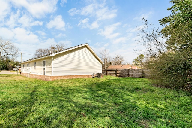 view of home's exterior with brick siding, a lawn, and fence