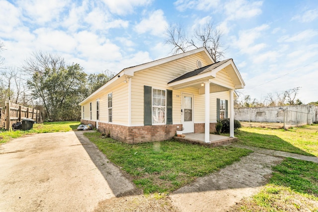 view of front of home featuring a front yard, brick siding, and fence