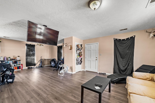 living area with visible vents, a textured ceiling, baseboards, and wood finished floors