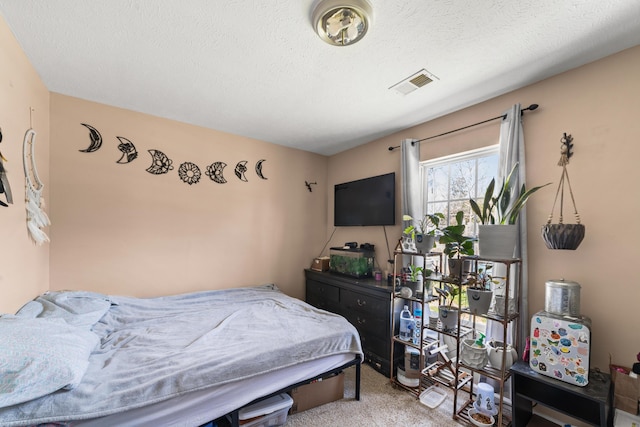 bedroom with a textured ceiling, carpet flooring, and visible vents