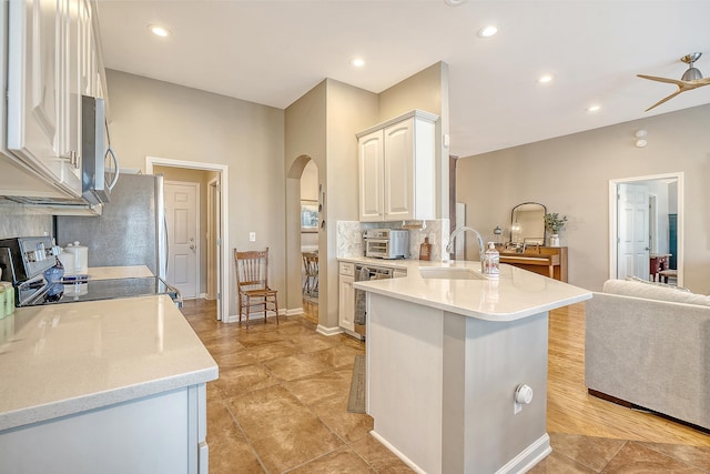 kitchen with ceiling fan, sink, backsplash, kitchen peninsula, and appliances with stainless steel finishes