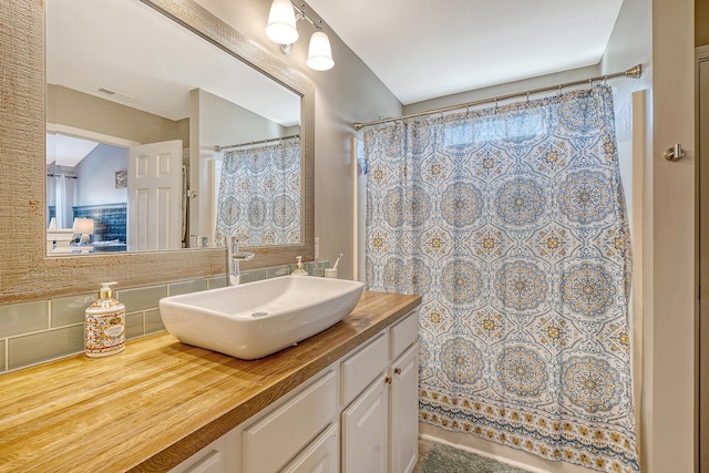 bathroom featuring tasteful backsplash, vanity, and lofted ceiling