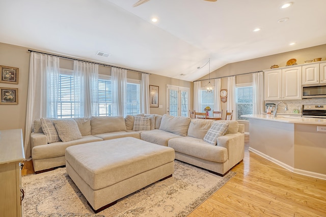 living room with light hardwood / wood-style floors, lofted ceiling, and an inviting chandelier