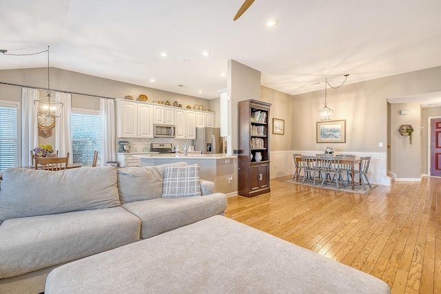 living room with light hardwood / wood-style floors, lofted ceiling, and a notable chandelier