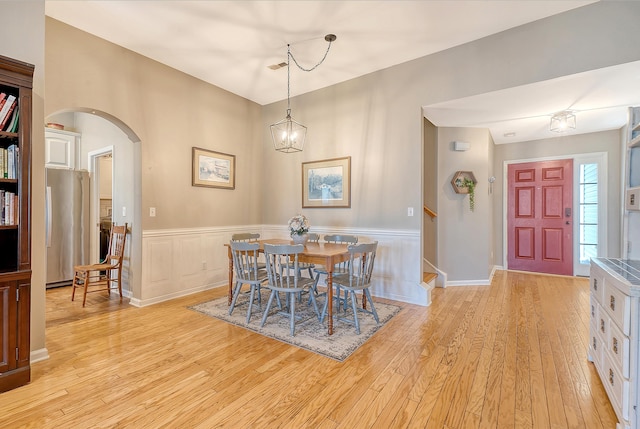 dining space with light hardwood / wood-style floors and an inviting chandelier