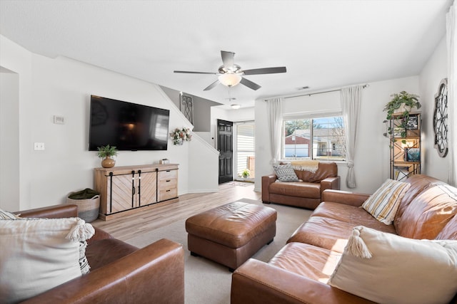 living room with ceiling fan, visible vents, and wood finished floors