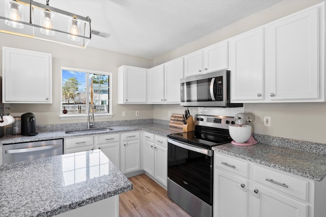 kitchen featuring a sink, white cabinetry, light wood finished floors, and stainless steel appliances