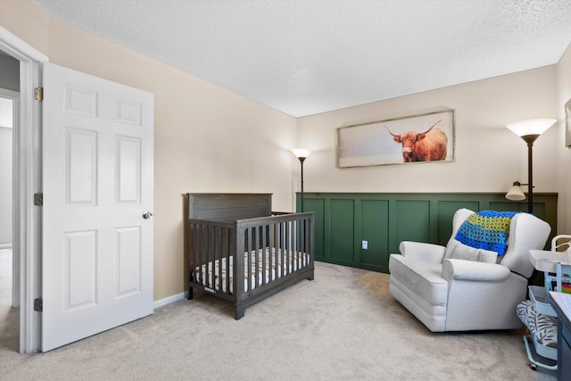 bedroom with light colored carpet, a textured ceiling, and a crib