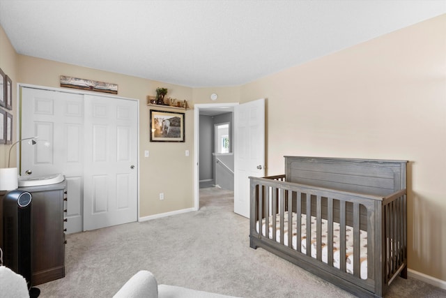 carpeted bedroom with a closet and baseboards