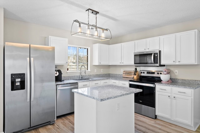 kitchen with white cabinets, appliances with stainless steel finishes, light wood-style flooring, and a sink