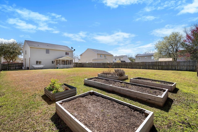 view of yard featuring a garden, a fenced backyard, and a residential view