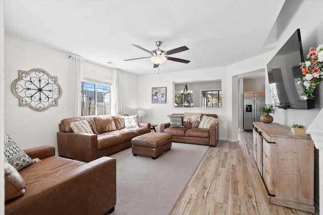 living room with ceiling fan with notable chandelier and light wood-type flooring